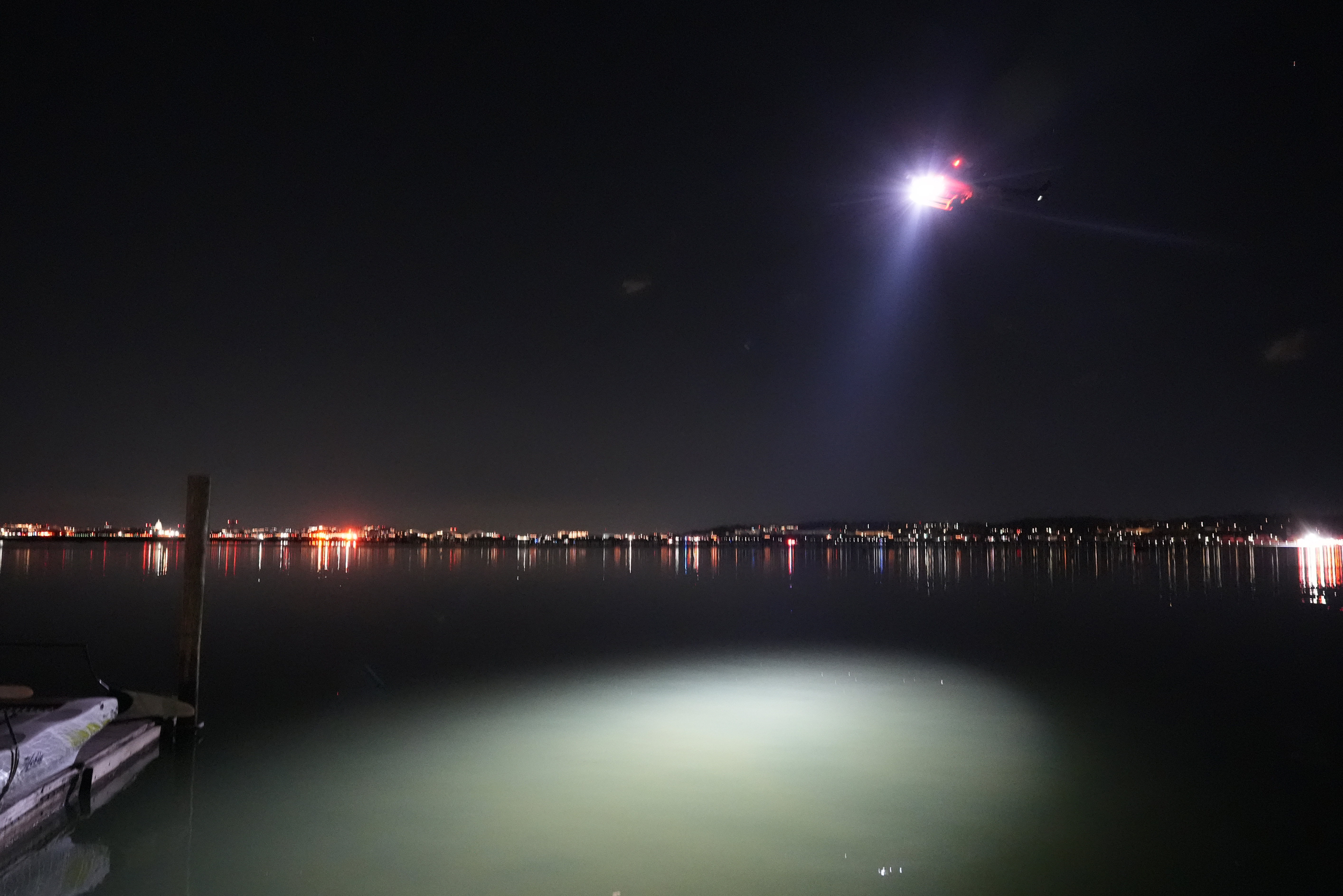 A helicopter uses a spotlight on the Potomac River near Ronald Reagan Washington National Airport, Thursday, Jan. 30, 2025, in Arlington, Va. (AP Photo/Alex Brandon)