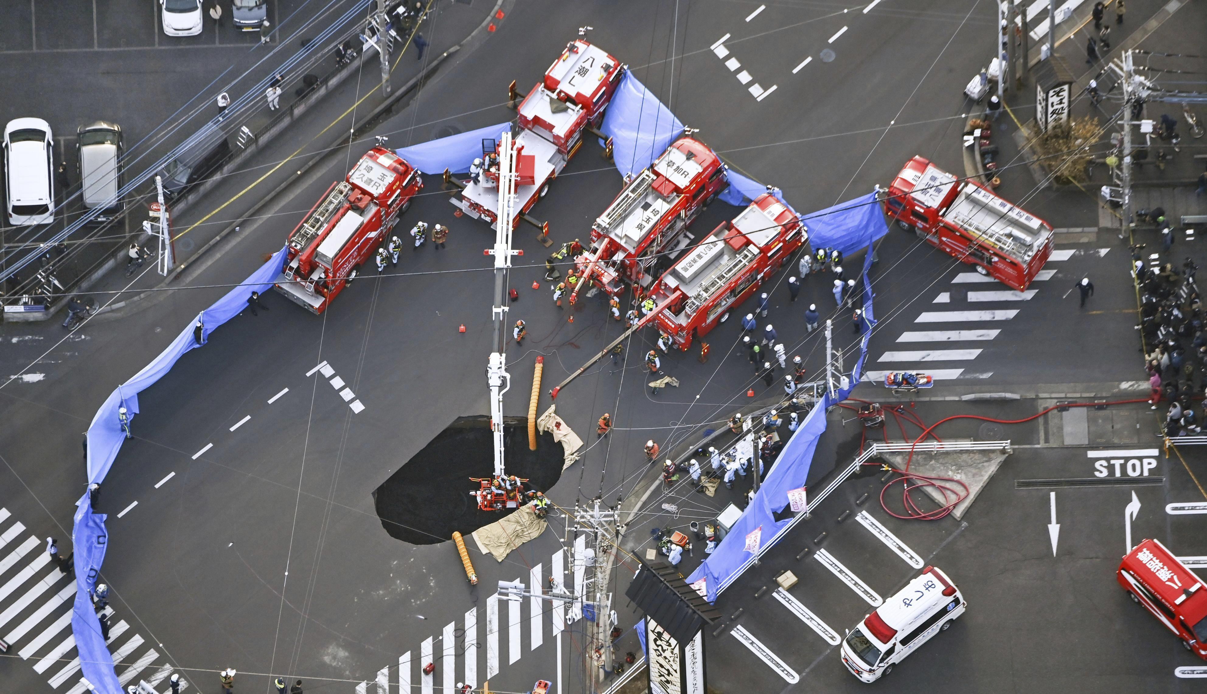 First responders try to rescue the driver of a truck that fell into a sinkhole on a street in Yashio, northeast of Tokyo, Tuesday, Jan. 28, 2025. (Kenichiro Kojima/Kyodo News via AP)