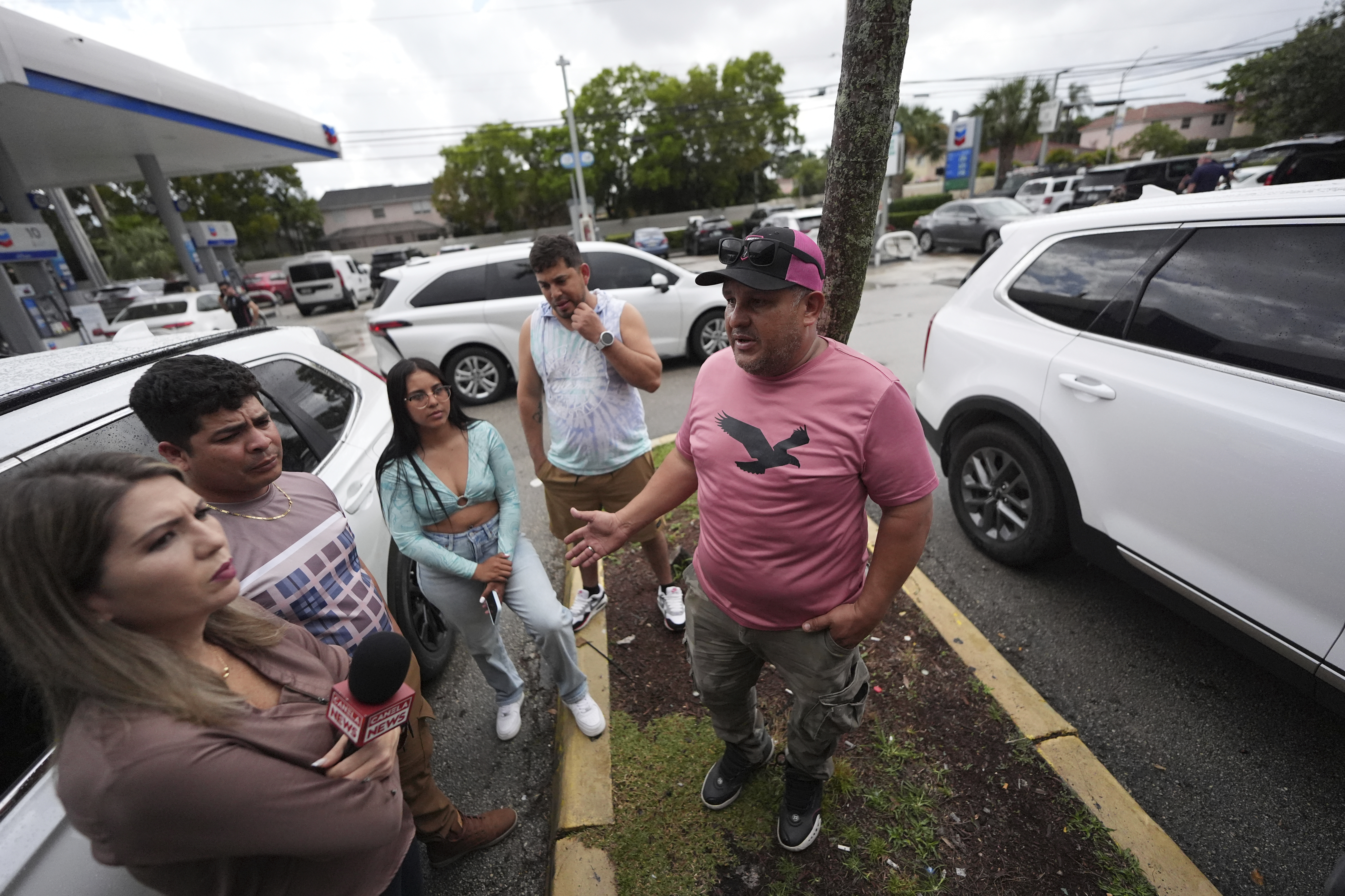 Henry Carmona, 48, right, who fled Venezuela after receiving death threats for refusing to participate in demonstrations in support of the government, stands with friends and a reporter following a press conference by Venezuelan community leaders to denounce changes to the protections that shielded hundreds of thousands of Venezuelans, including Carmona, from deportation, Monday, Feb. 3, 2025, in Doral, Fla. (AP Photo/Rebecca Blackwell)