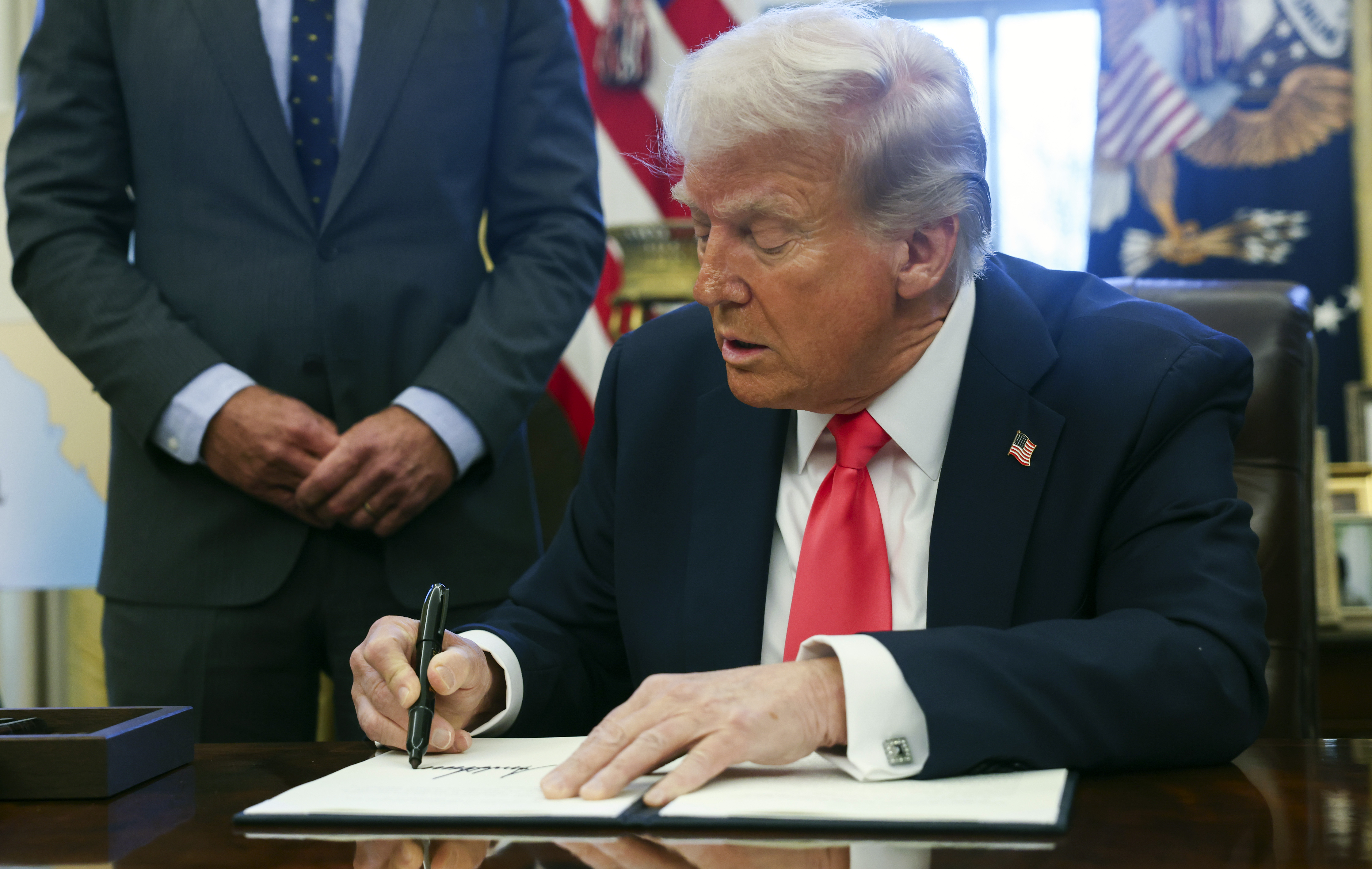 President Donald Trump signs an executive order in the Oval Office at the White House in Washington, Tuesday, Feb. 25, 2025. (Pool via AP)