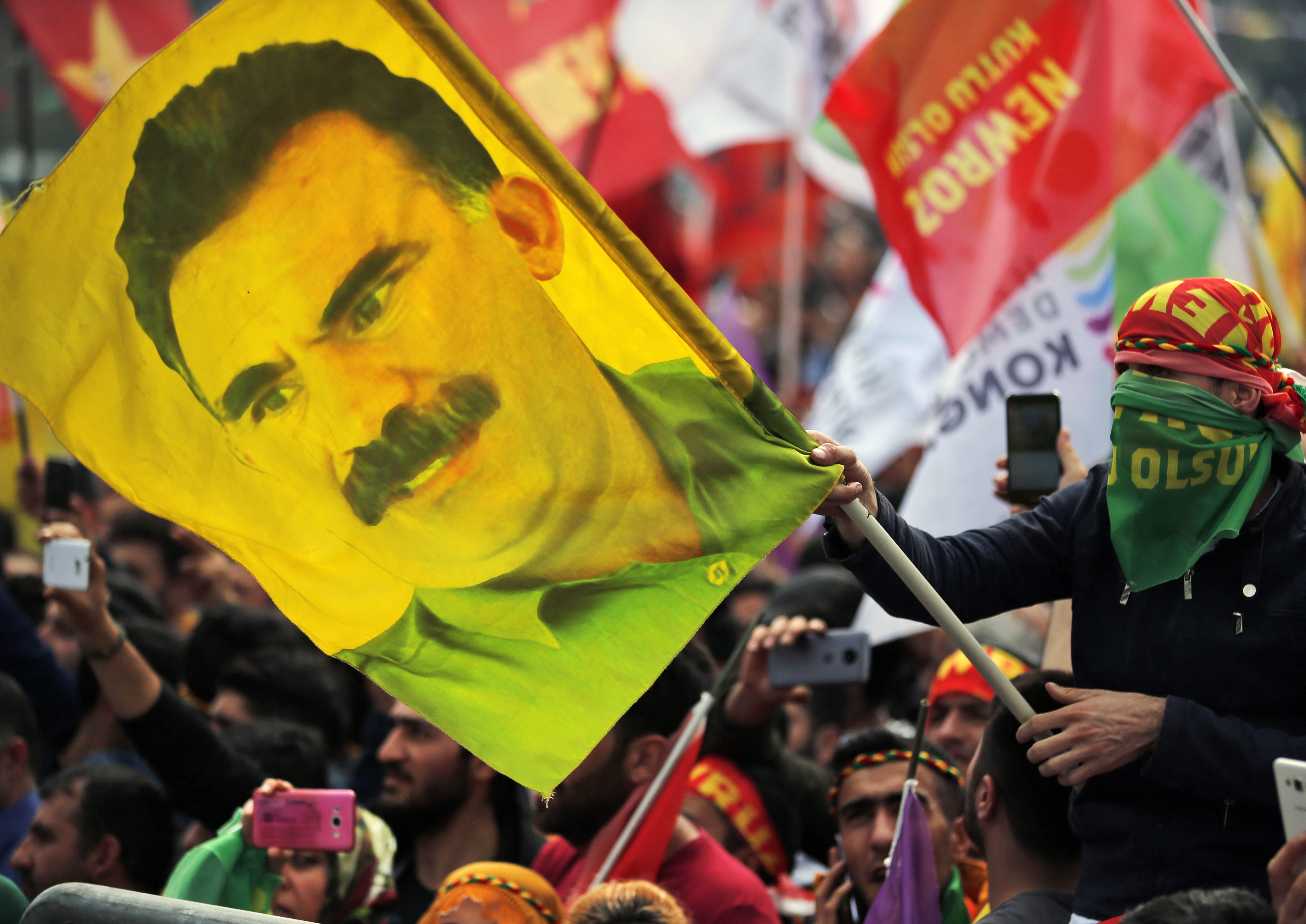 FILE - In this file photo dated Wednesday, March 21, 2018, a youth holds a flag with the image of Abdullah Ocalan, the jailed leader of the rebel Kurdistan Workers' Party, or PKK, in Istanbul, Turkey. (AP Photo/Lefteris Pitarakis, File)